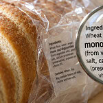 Sliced white bread in a plastic bag, with a magnifying glass over the ingredient label showing mono- and diglycerides