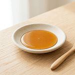 A jar of honey beside a wooden beehive, representing the debate over whether vegans should eat honey.